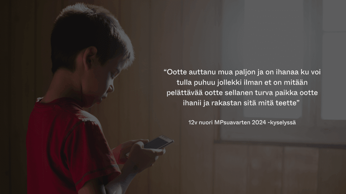 lyhyttukkainen, noin 6-vuotias lapsi seisoo seinän vieressä ja katsoo puhelintaan.